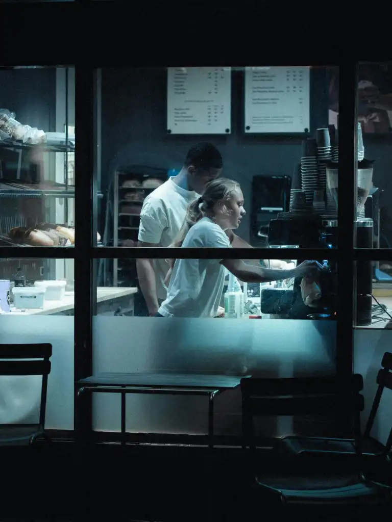 Bakers working in the bakery kitchen seen through the window at night